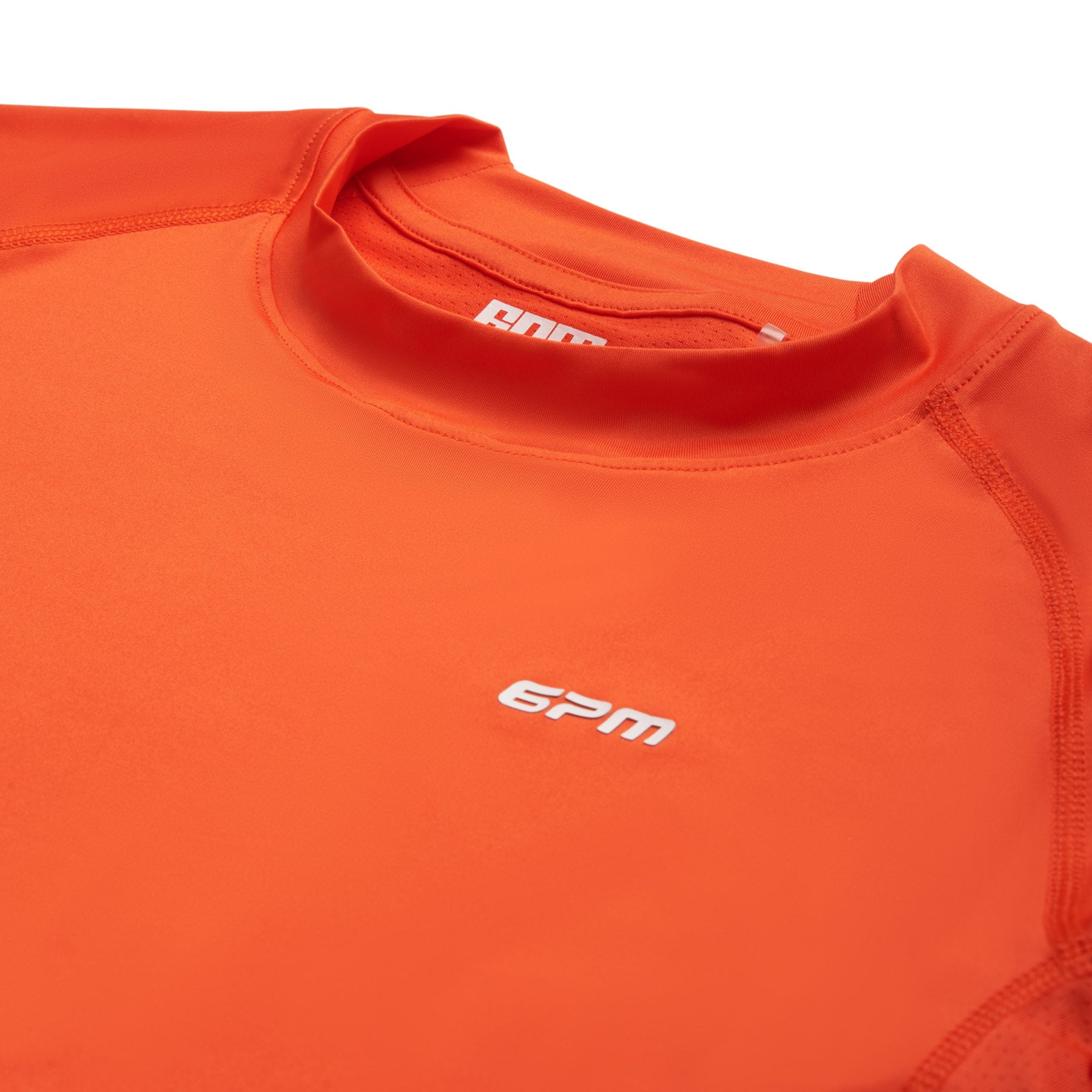 Close-up of the 6PM SPORTS T-SHIRT SUNSTONE RED by 6PM, featuring a white 6PM logo on the chest and inside the collar with visible stitching along the shoulders and seams.