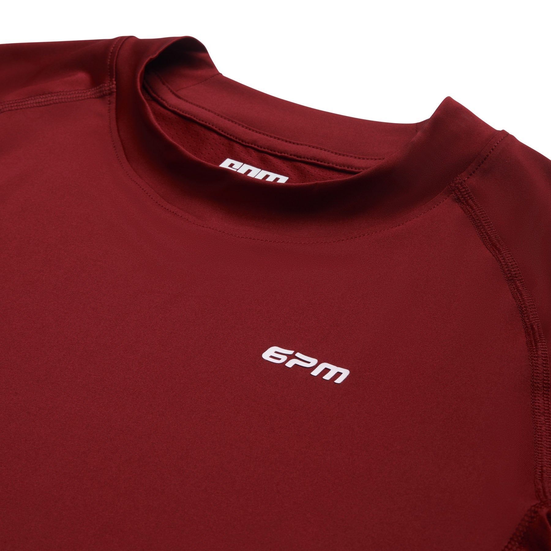 A close-up of the 6PM SPORTS T-SHIRT WINE RED by 6PM, featuring a small white logo on the left chest, a crew neckline, and smooth, stretchy fabric.