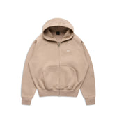The 6PM ZIP HOODIE MOCCA CREAM is a beige zip-up hoodie with a front pocket, hood, and minimalist design. It features a small embroidered logo on the left chest and a clean finish, perfect for everyday wear. Laid flat on a white background.