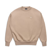 The 6PM CREWNECK MOCCA CREAM is a beige crewneck sweatshirt with long sleeves and ribbed collar, cuffs, and hem. It features a small white logo on the left chest, set against a white background.