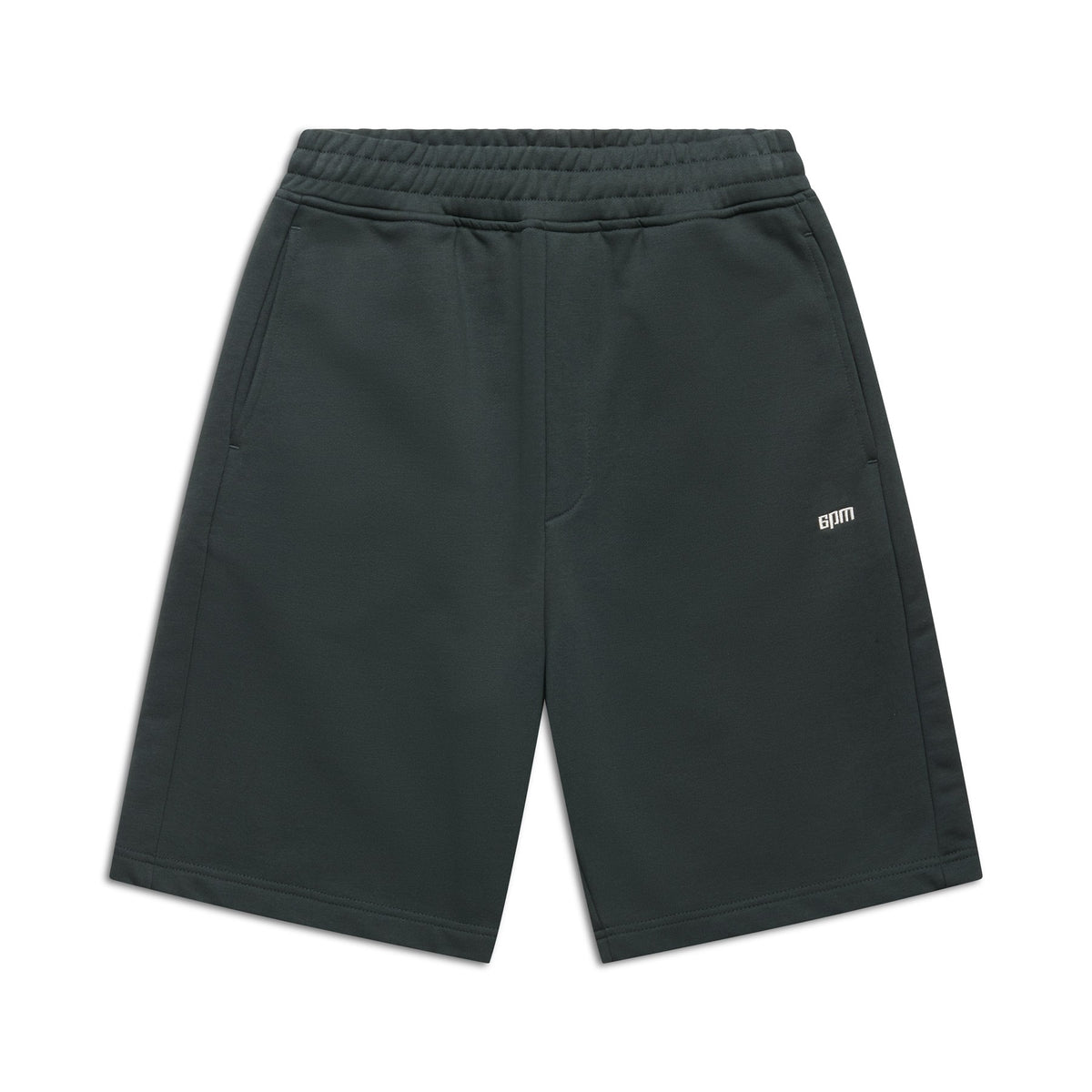 The 6PM+ SHORTS DARK EMERALD by 6PM are knee-length athletic shorts in dark emerald with a soft brushed interior, elastic waistband, side pockets, and a small white BDM logo on the left thigh, shown on a white background.