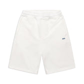 6PM+ SHORTS COCONUT WHITE by 6PM: white athletic shorts featuring a relaxed fit, elastic waistband, side pockets, and a small blue spm logo on the left thigh—ideal for lounging. Shown flat on a white background.