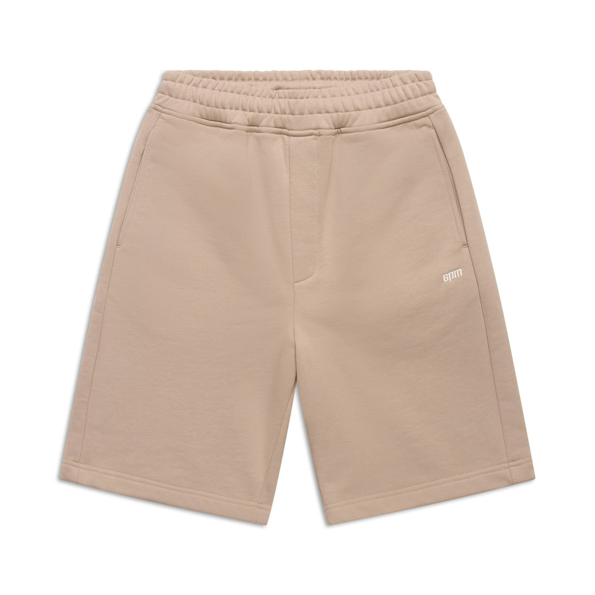 The 6PM+ SHORTS MOCCA CREAM by 6PM are beige, knee-length with a relaxed fit, elastic waistband, side pockets, and a small white embroidered logo on the left thigh—ideal for lounging. Shown flat on a white background.