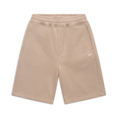 The 6PM+ SHORTS MOCCA CREAM by 6PM are beige, knee-length with a relaxed fit, elastic waistband, side pockets, and a small white embroidered logo on the left thigh—ideal for lounging. Shown flat on a white background.