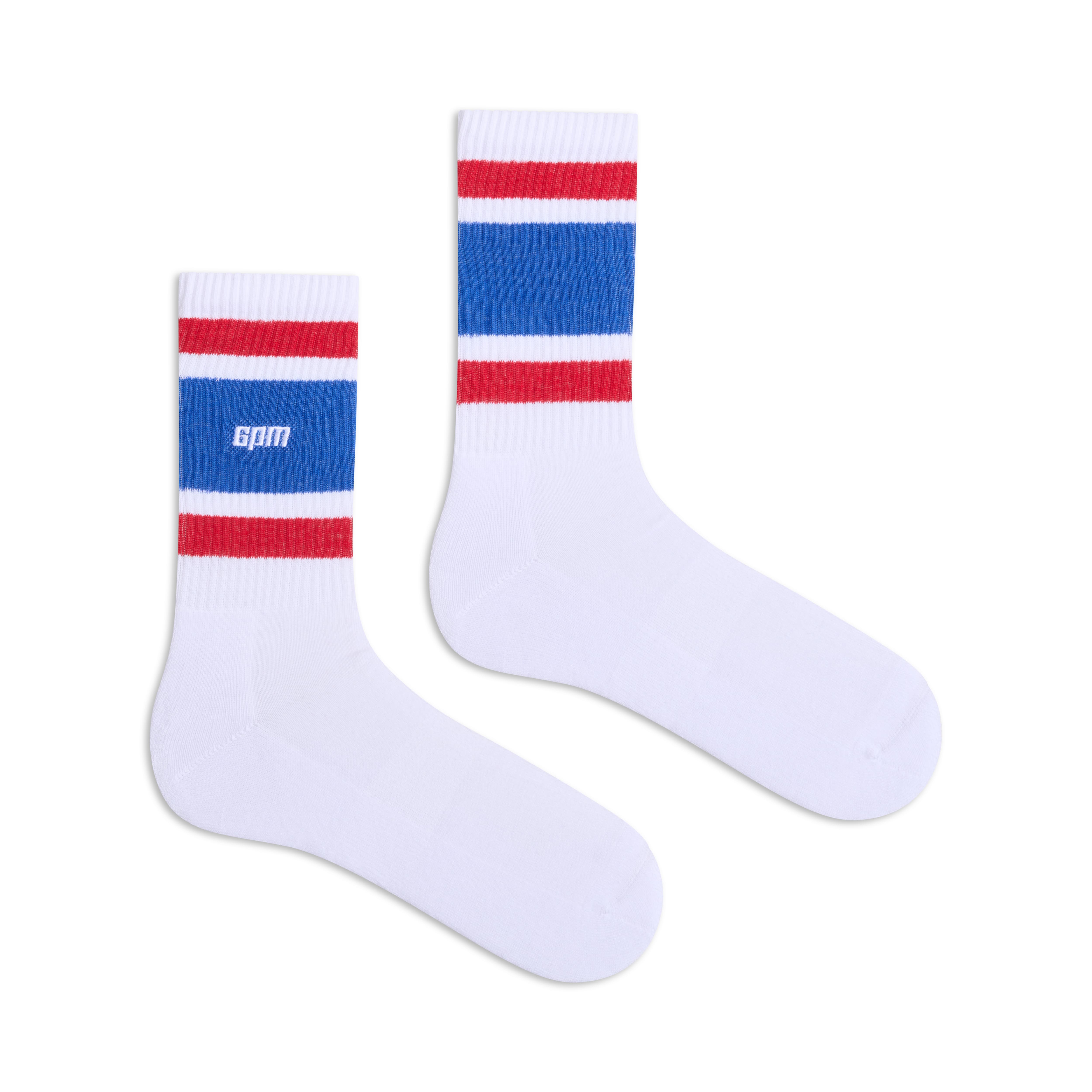 The 6PM LOGO TUBE SOCKS WHITE are white crew socks featuring thick blue and red stripes near the top and GAM text in white on the side of one sock.