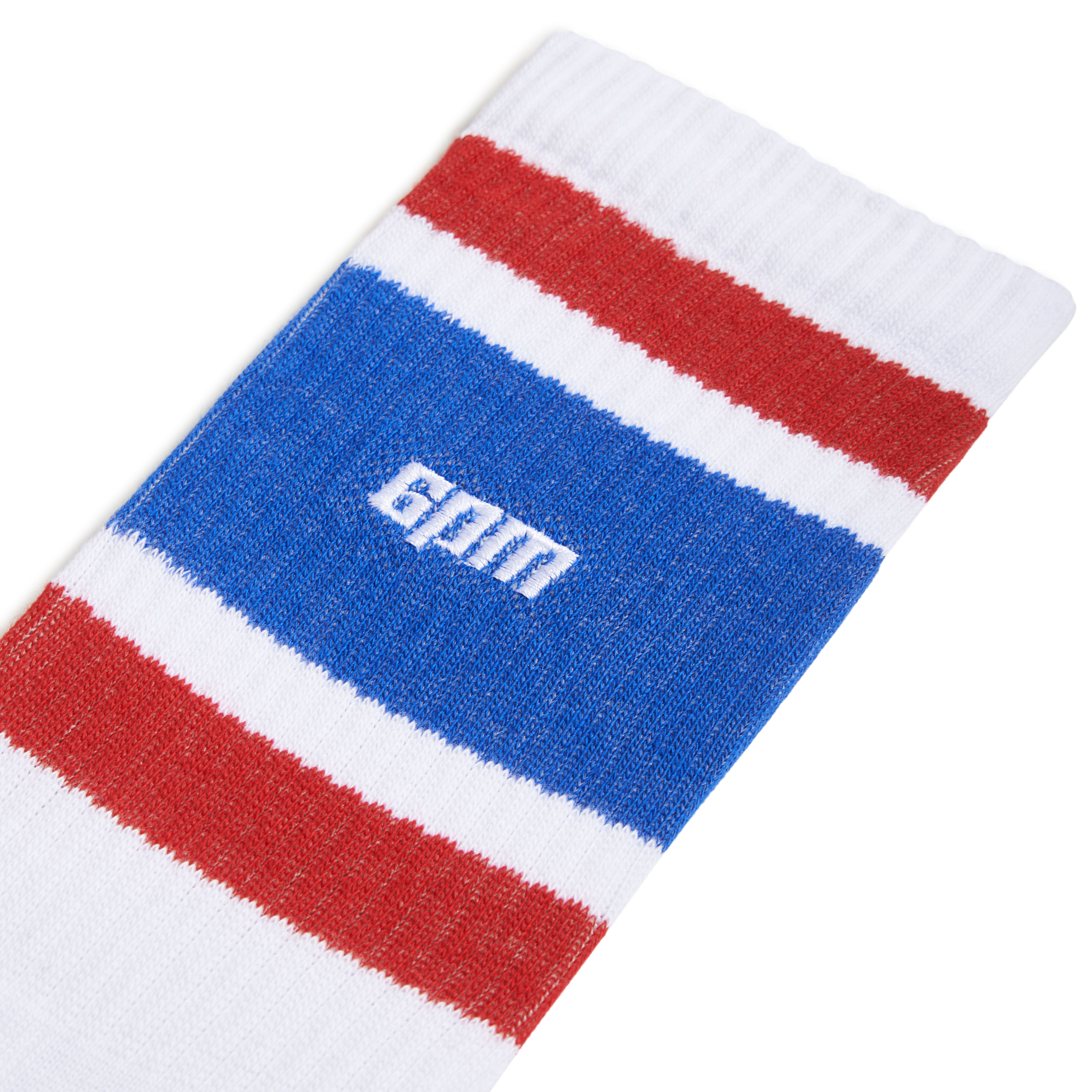 A close-up of 6PMs LOGO TUBE SOCKS WHITE, showing ribbed fabric with horizontal red, white, and blue stripes and the word GUM stitched in white on the blue stripe.