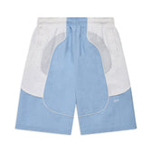 The BAGGY WARM UP SHORTS ICE BLUE by 6PM feature light blue and white color blocking, an elastic waistband, side pockets, and a small CPFM logo on the lower left leg. The shorts are shown laid flat on a white background.