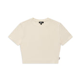 The 6PM WMNS CROPPED T-SHIRT OFF-WHITE is a plain, short-sleeved cropped tee in off-white, shown flat on a white background with a small fabric tag on the left and a black neck label.