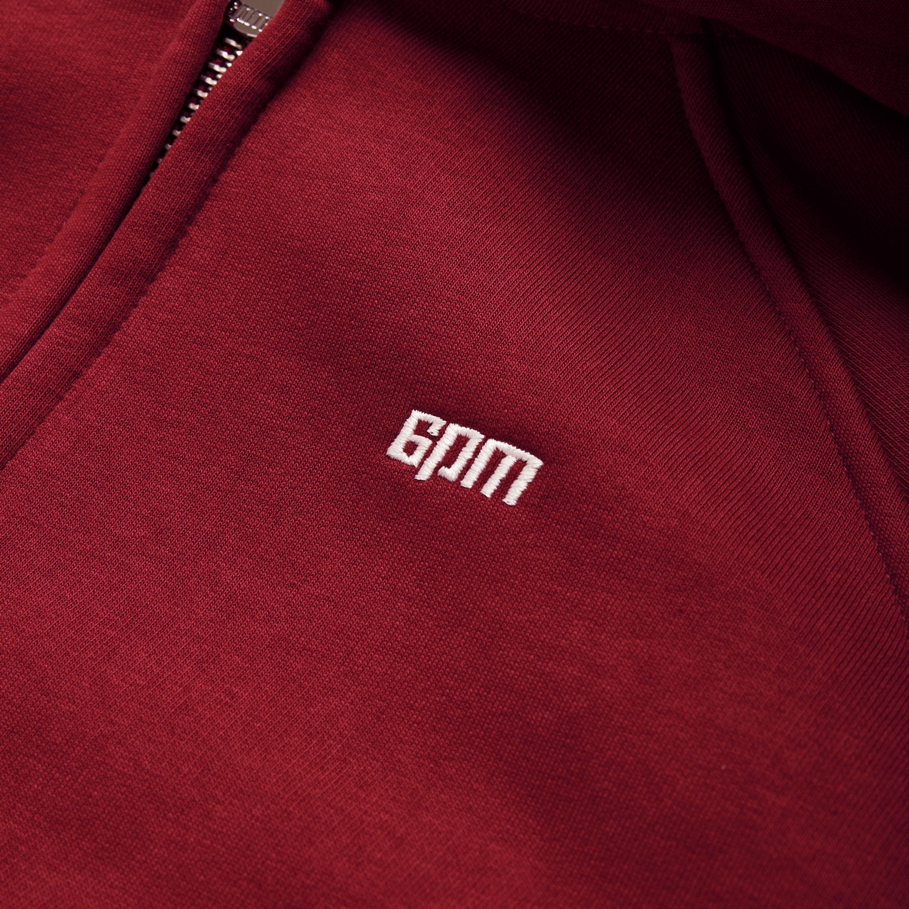 Close-up of the WMNS CROPPED ZIP HOODIE in wine red by 6PM, featuring a visible zipper and white embroidered 6PM branding on the chest.