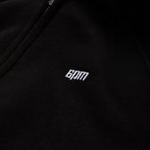 Close-up of black fabric from the 6PM WMNS CROPPED ZIP HOODIE BLACK, featuring a small white embroidered 6PM logo.