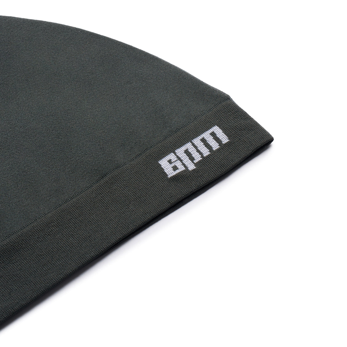 A close-up of the TECHNICAL LOGO BEANIE DARK EMERALD by 6PM shows a white embroidered logo near the edge against a plain white background.
