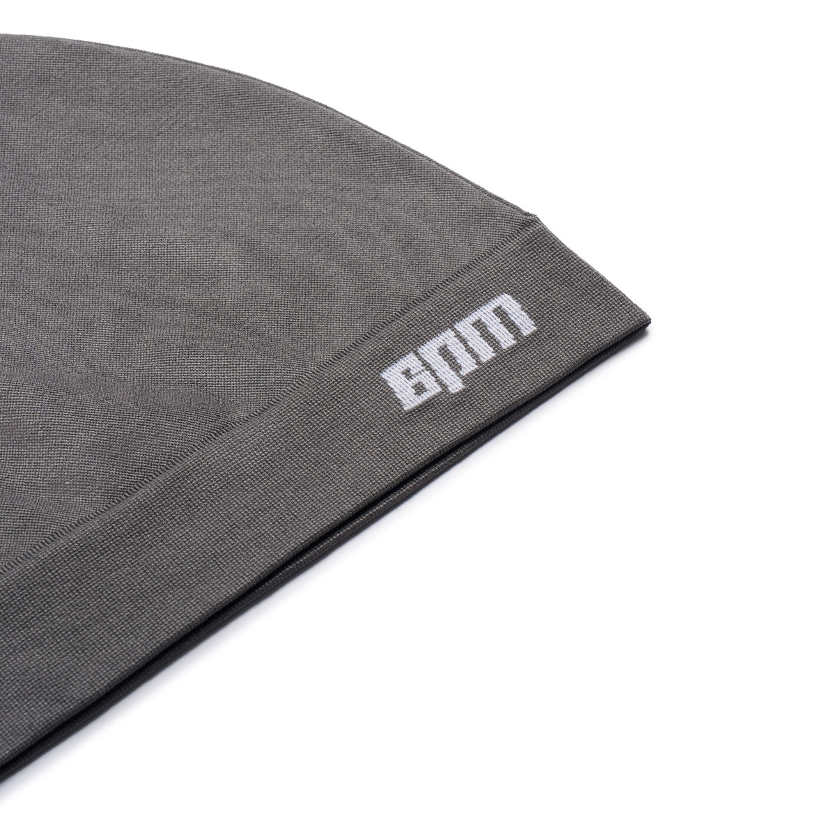 A close-up of the TECHNICAL LOGO BEANIE ANTHRACITE by 6PM, featuring BAM embroidered in white on the cuff, displayed against a white background.