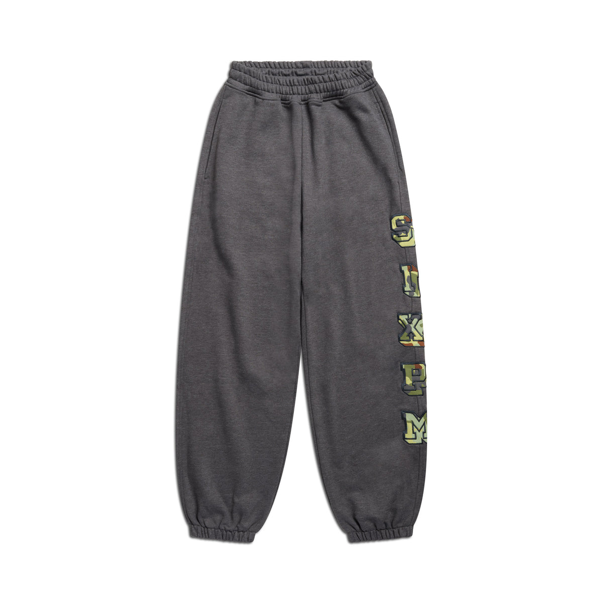 The 6PM SUPER WIDE JOGGER GREY CAMO features dark gray camo sweatpants with an elastic waistband and cuffs, and bold yellow-green varsity-style letters running vertically down the left leg, shown on a white background.