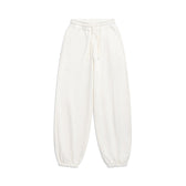 The 6PM SUPER WIDE JOGGER COCONUT WHITE features an elastic waistband with drawstring, side pockets, and elastic ankle cuffs, shown laid flat on a white background.