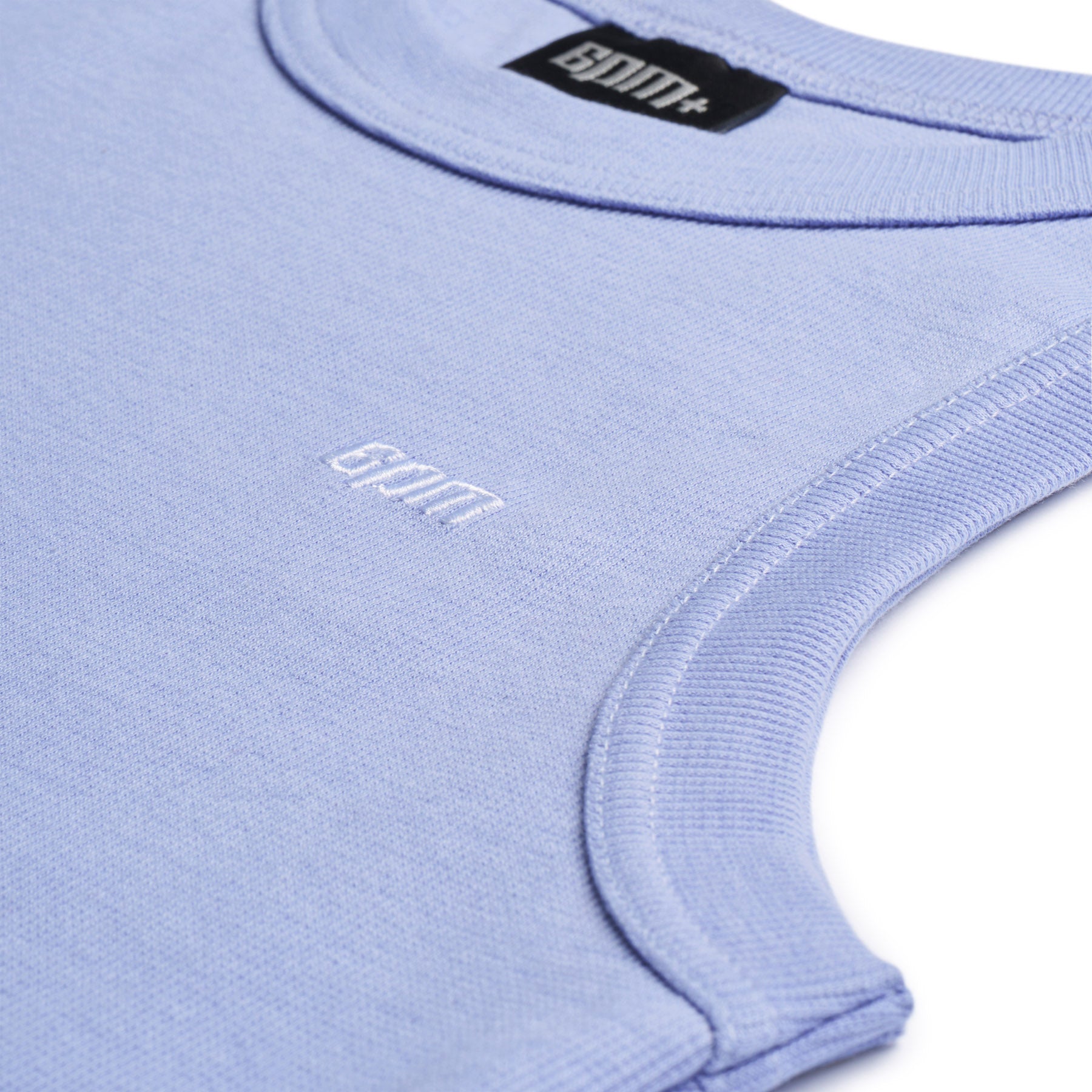 Close-up of the 6PM TANK TOP SOFT VIOLET, a sleeveless violet knit top with ribbed trim, featuring a small white chest logo and a black label with white text inside the neckline.