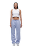 A woman with braided hair and a neutral expression faces forward in a white setting, wearing the 6PM WMNS OPEN LEG SOFT VIOLET pants with a white cropped tank top and white sneakers.