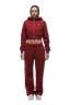 A person faces forward wearing the 6PM WMNS Cropped Zip Hoodie in Wine Red paired with matching sweatpants and white sneakers. The hoodie features a small white logo on the left chest. The background is white.