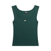 The 6PM WMNS TANKTOP EVERGREEN features a sleeveless, dark green design with a round neckline, accented by a small oval metallic detail on the chest and a black collar label, shown against a white background.